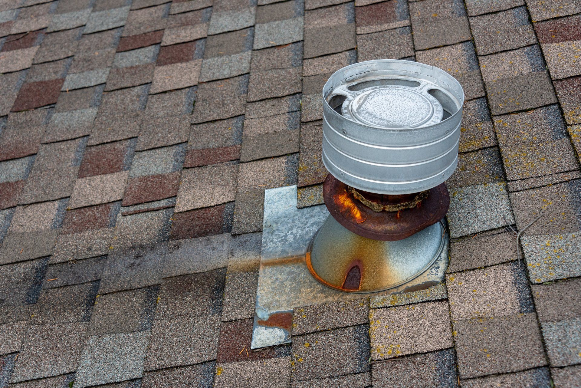 A rusty roof vent on top of a brick roof.