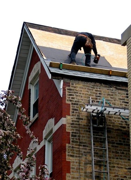 A man is working on the roof of a brick building