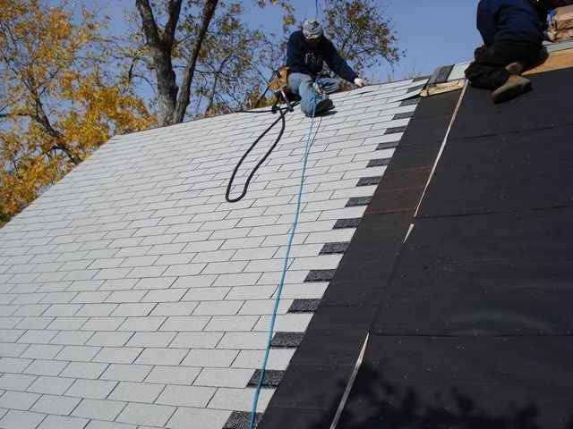 A man is working on a roof with a rope attached to him.