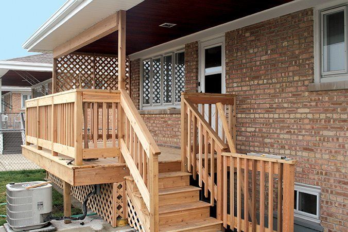 A brick house with a wooden deck and stairs.