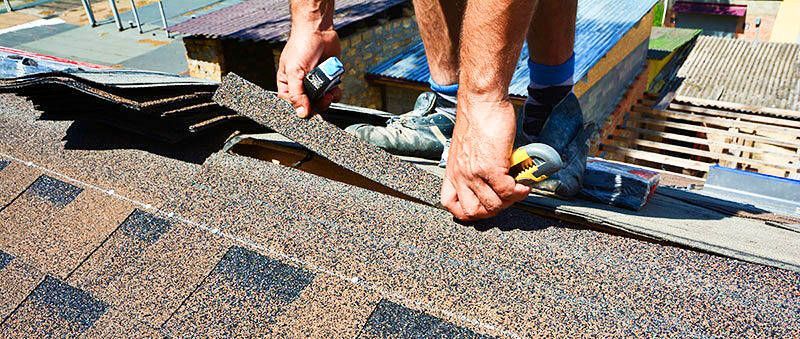 A man is installing shingles on a roof.