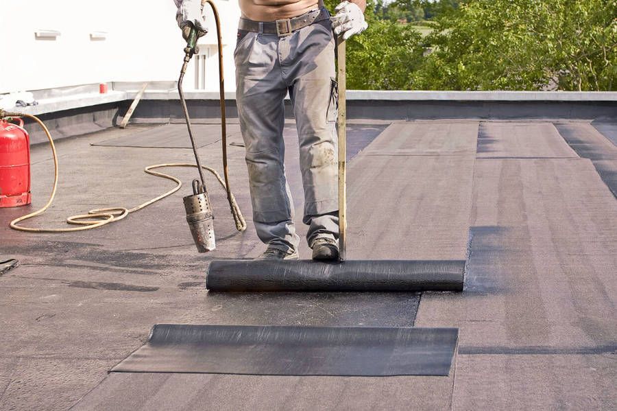 A man is working on a roof with a torch.