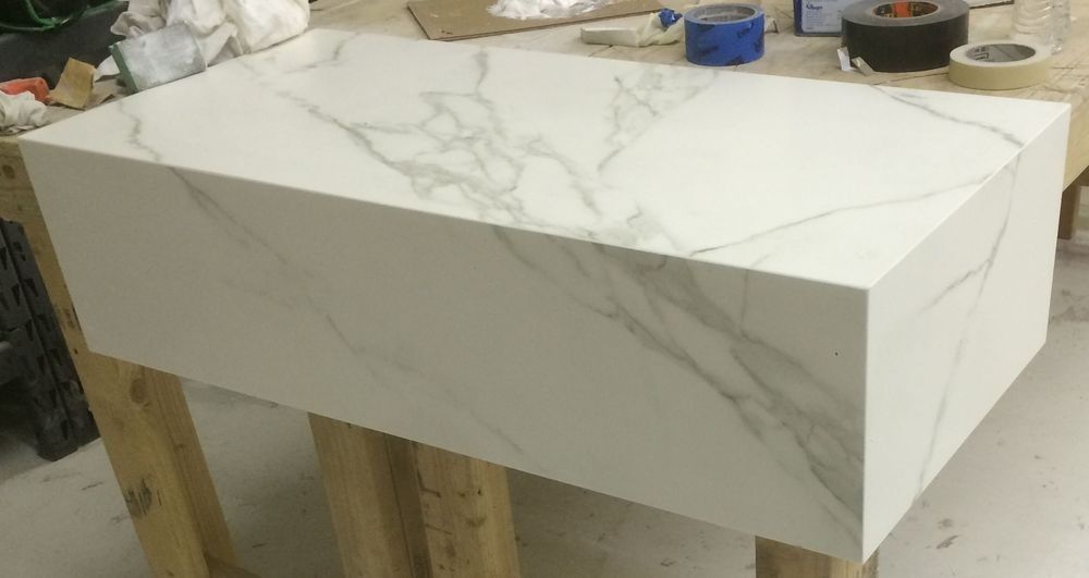 A white marble counter top is sitting on top of a wooden table