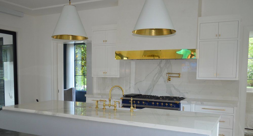 A kitchen with white cabinets and gold appliances