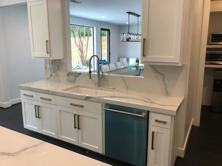 A kitchen with white cabinets and a blue dishwasher
