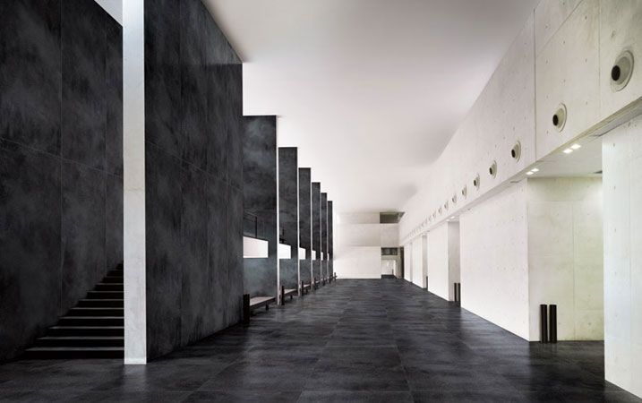 A long hallway with stairs and a black floor