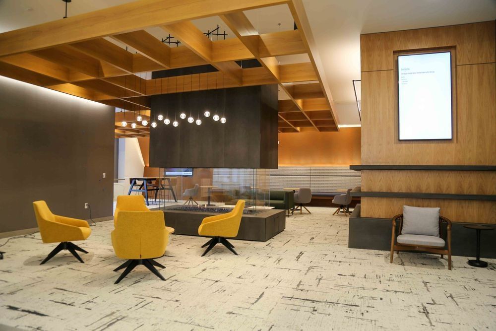 A lobby with yellow chairs and a fireplace