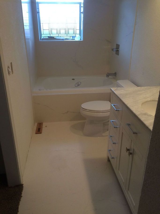 A bathroom with a toilet, sink, tub and window