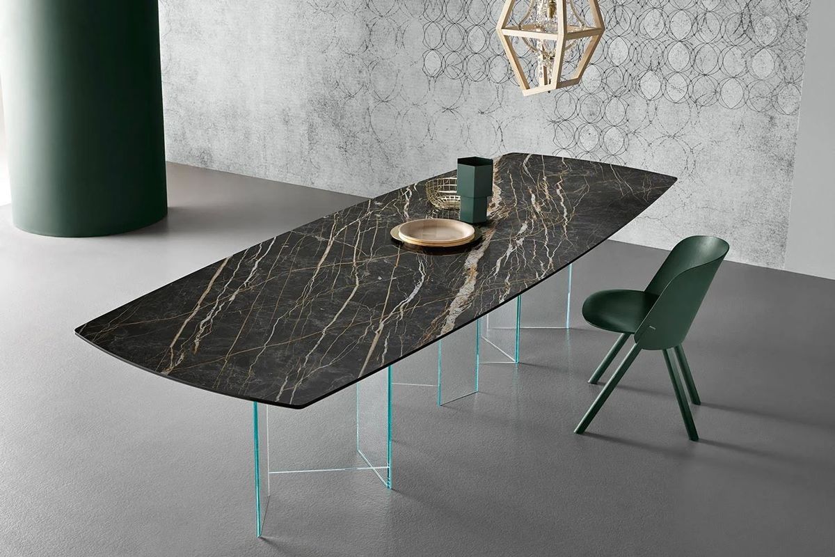 A long table with a marble top and glass legs in a room