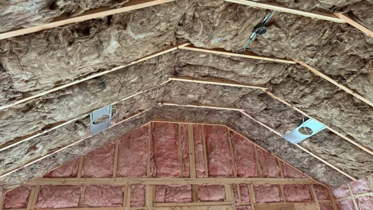 The ceiling of a house is covered in insulation and wooden beams.