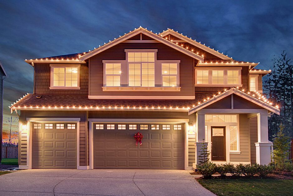 A house is decorated with christmas lights and has two garage doors