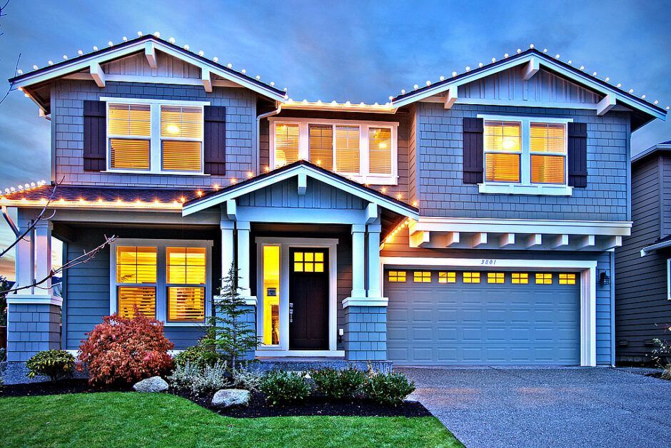 A large blue house with christmas lights on the roof