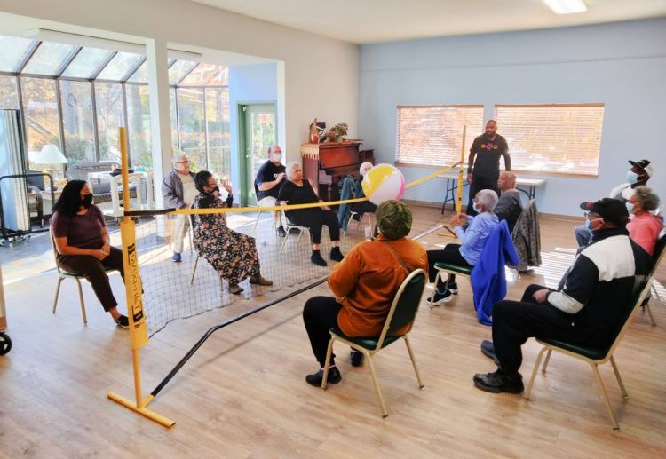 Community center activity in Seattle, showing participants engaged in a fun game of sitting volleyball, promoting social interaction and active living.