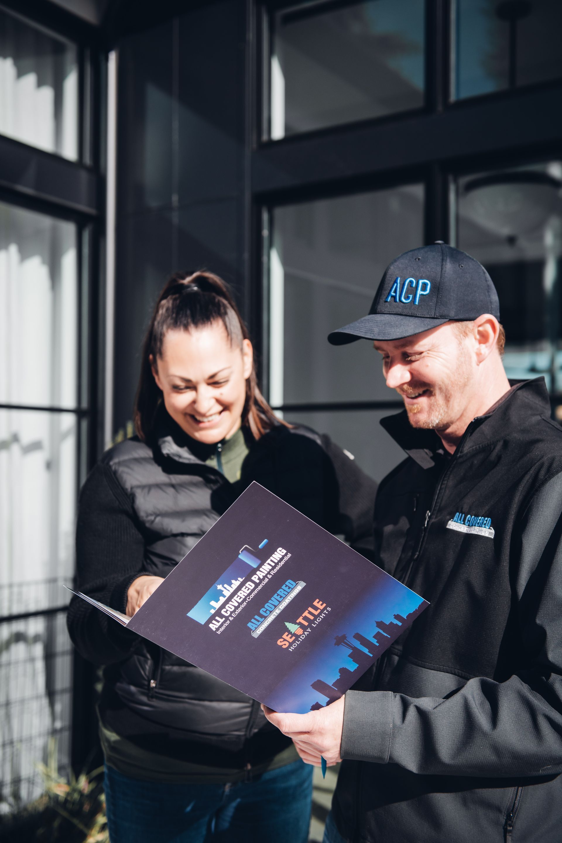 A man and a woman are standing next to each other looking at a folder.