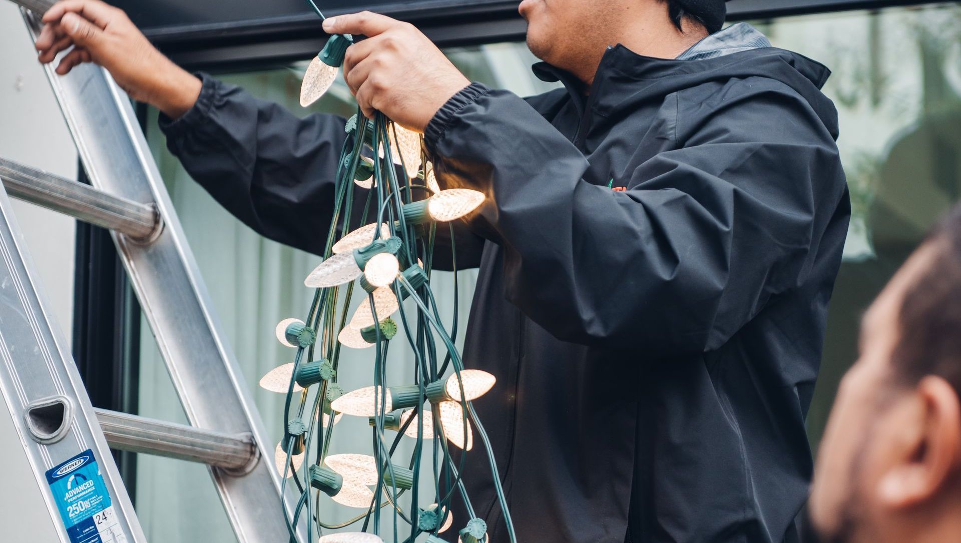 Professional holiday light installation Seattle - technician installing Christmas lights on residential home by