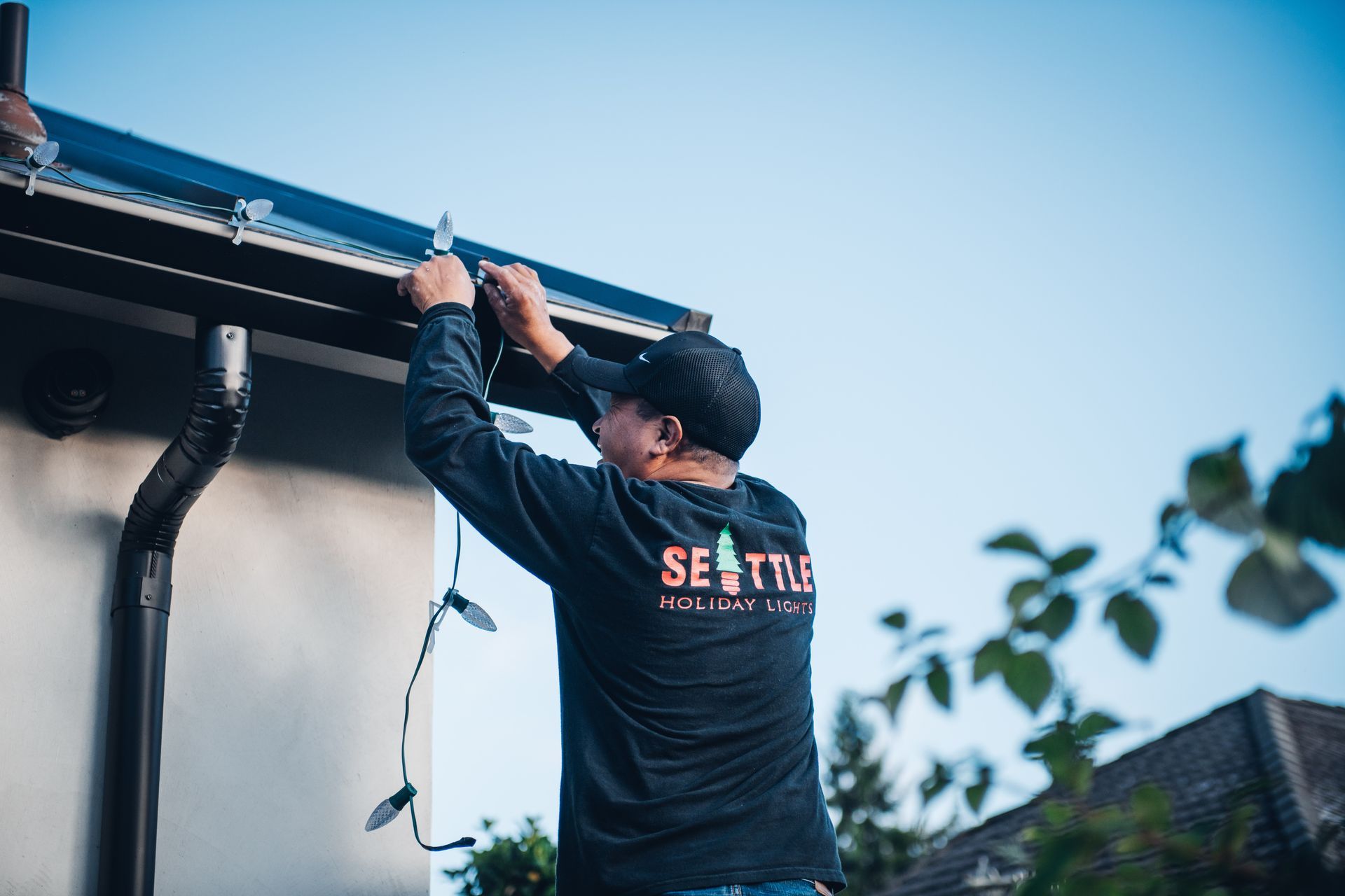 A man is fixing a gutter on the side of a house.