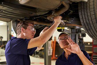 Rebuild Transmissions — Mechanic And Male Trainee Working Underneath Car in Oldsmar, FL
