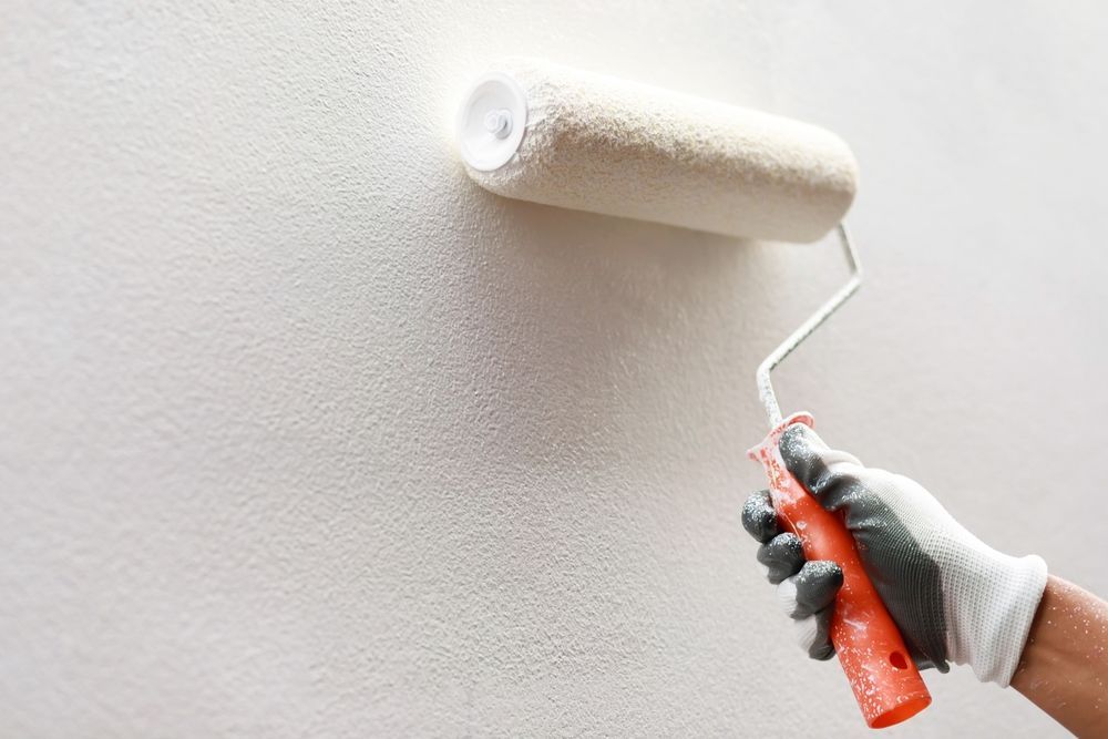 A person is painting a wall with a paint roller.