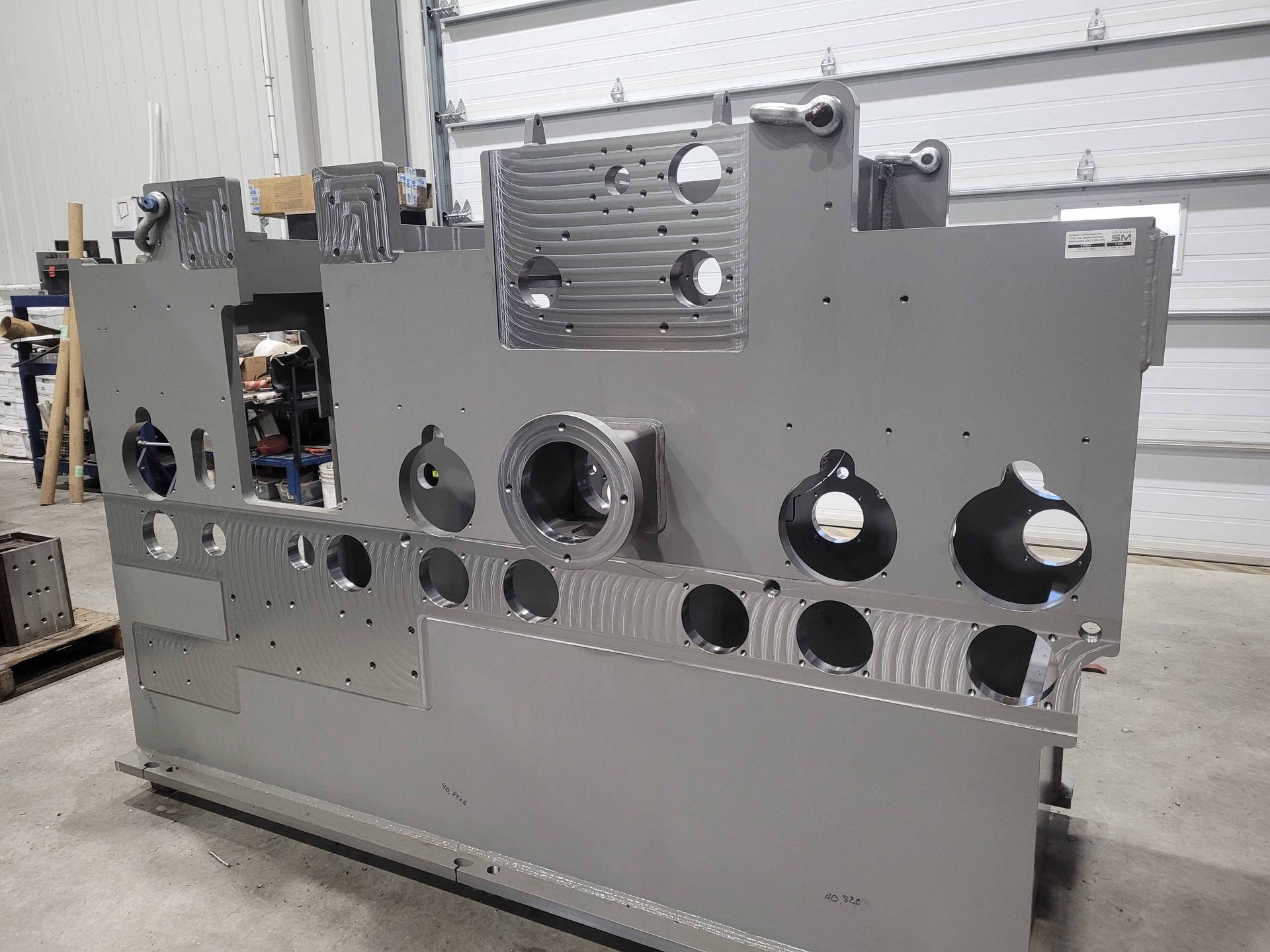 Une grande machine grise est assise dans un garage à côté d'une porte de garage.