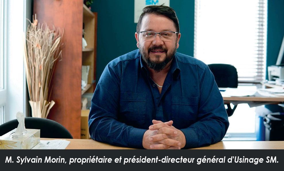Un homme avec une barbe est assis à un bureau, les mains jointes