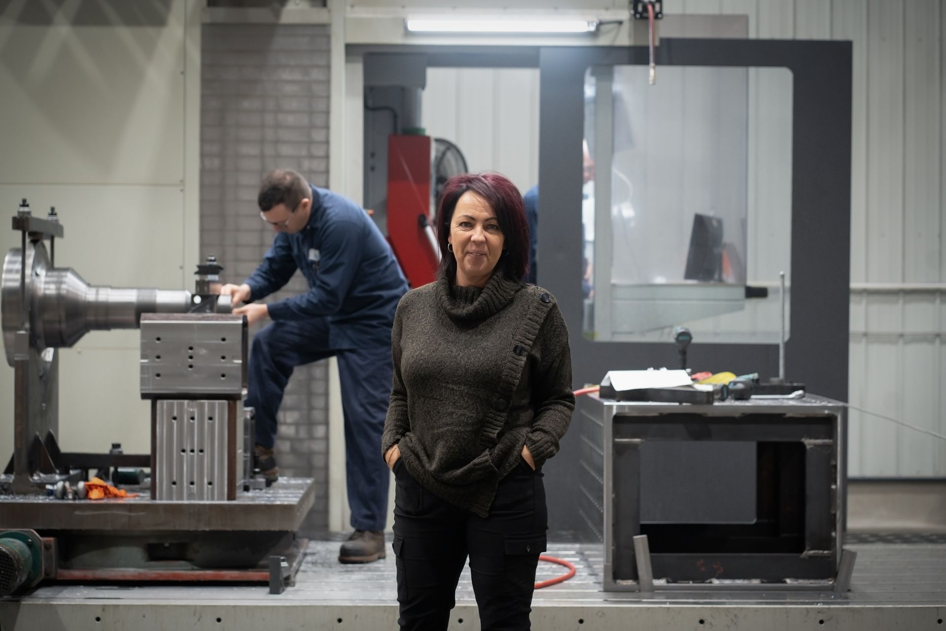 Une femme se tient devant une machine dans une usine.