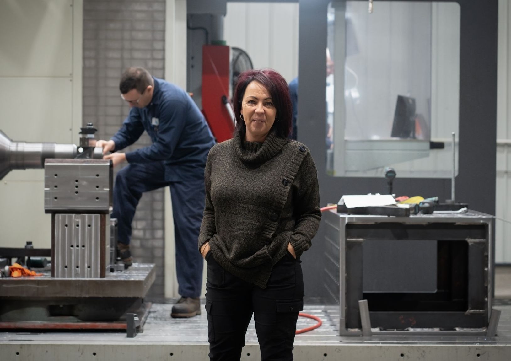 Une femme se tient devant une machine dans une usine.