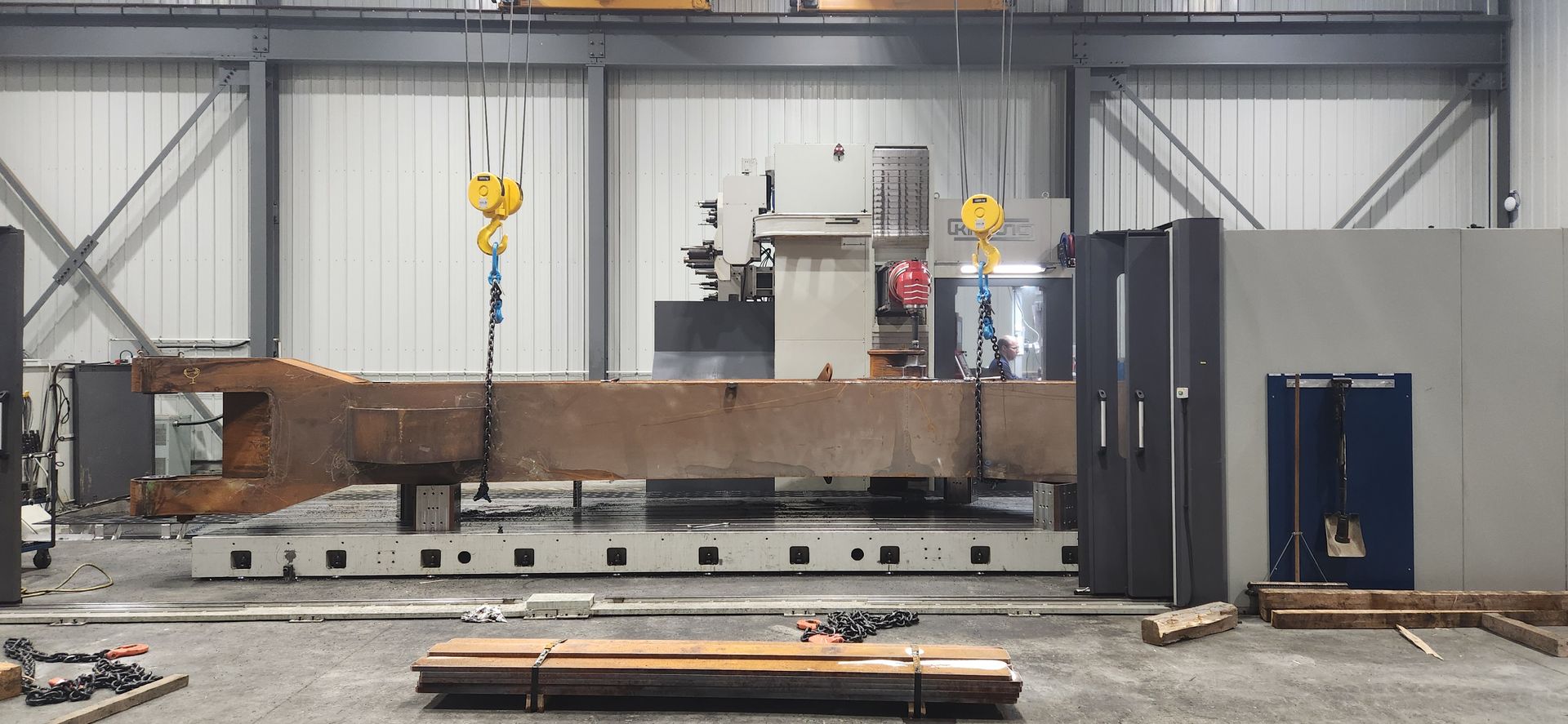 Un gros morceau de métal est soulevé par une grue dans une usine.