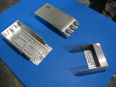 Trois morceaux de métal sont posés sur un tapis bleu et l'un d'eux porte la lettre a