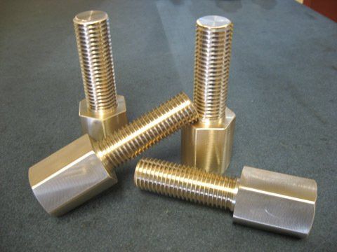 Quatre boulons en laiton sont empilés les uns sur les autres sur une table