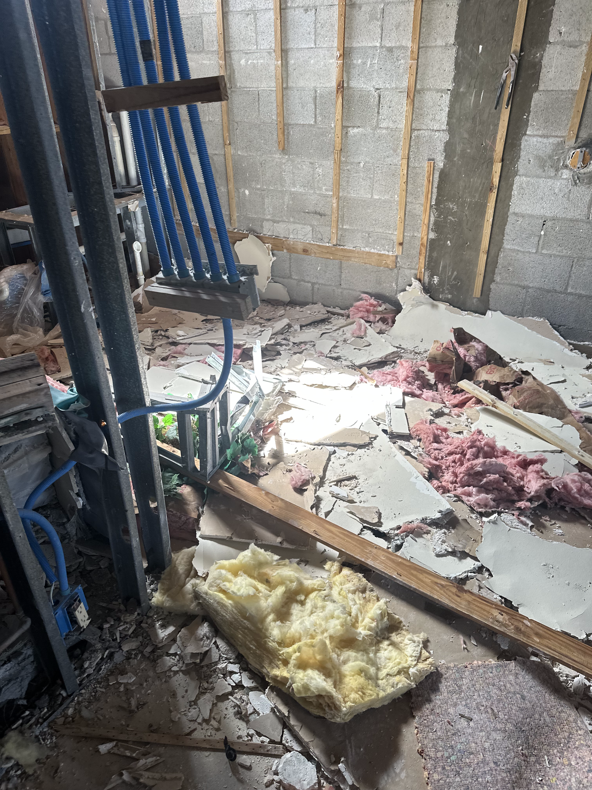 A room with a lot of broken pieces of concrete and insulation on the floor.