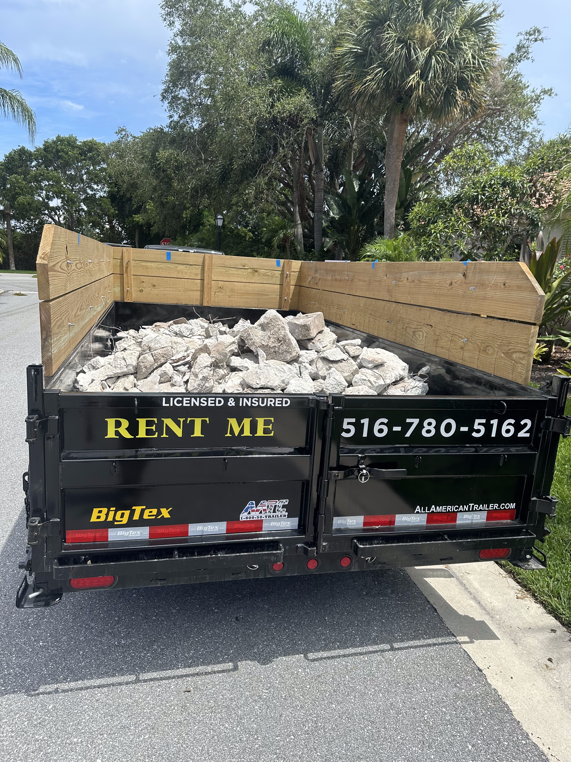 A dumpster filled with rocks is parked on the side of the road.