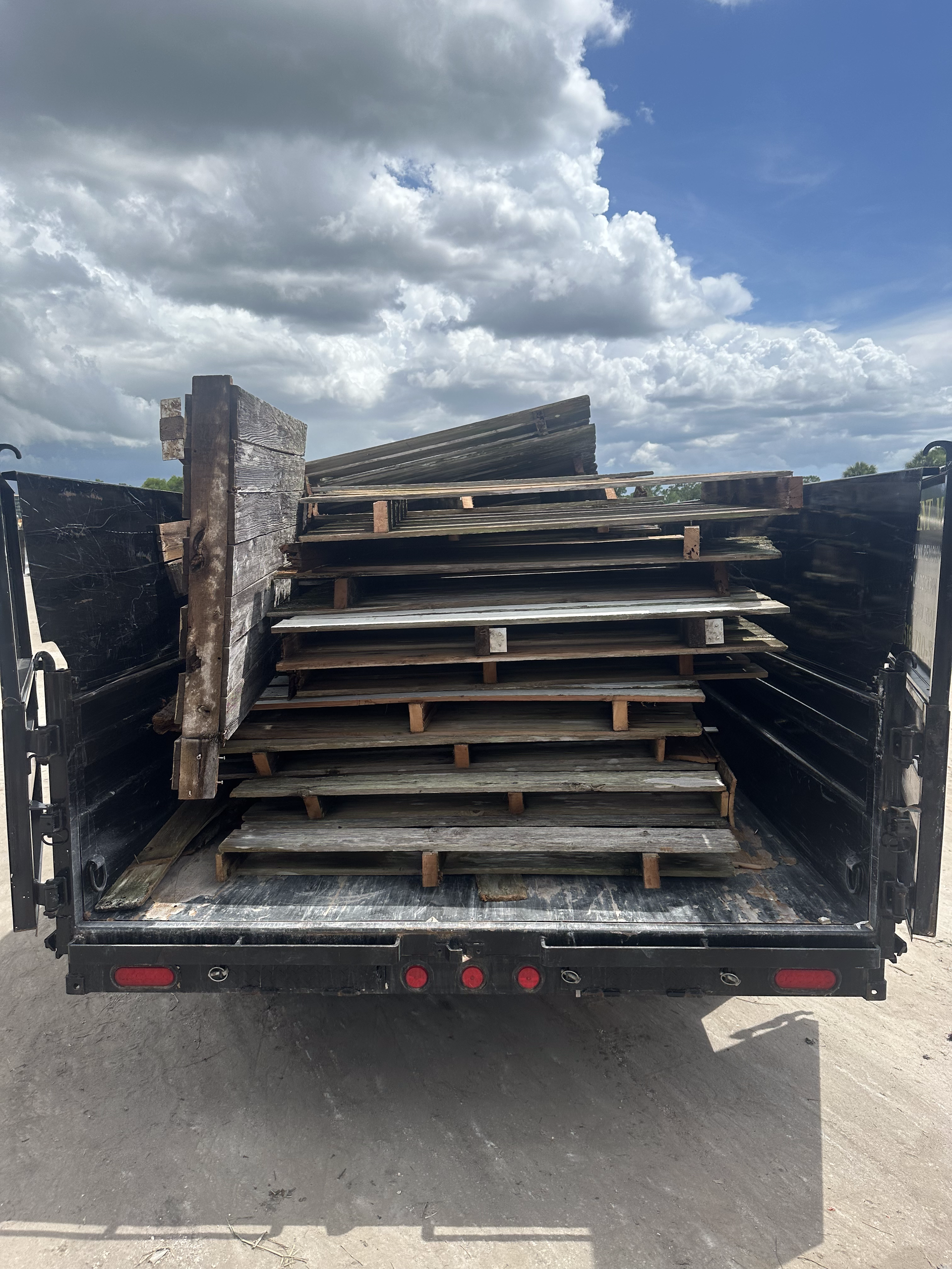 The back of a truck filled with wooden pallets.