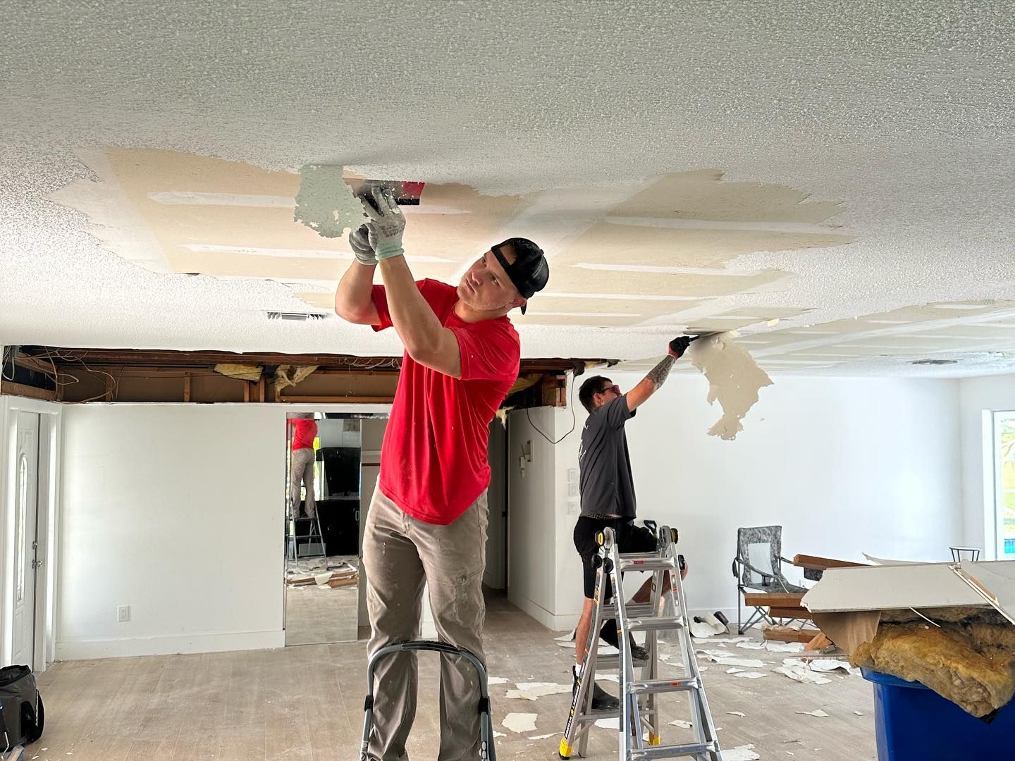 Two men are working on the ceiling of a house.