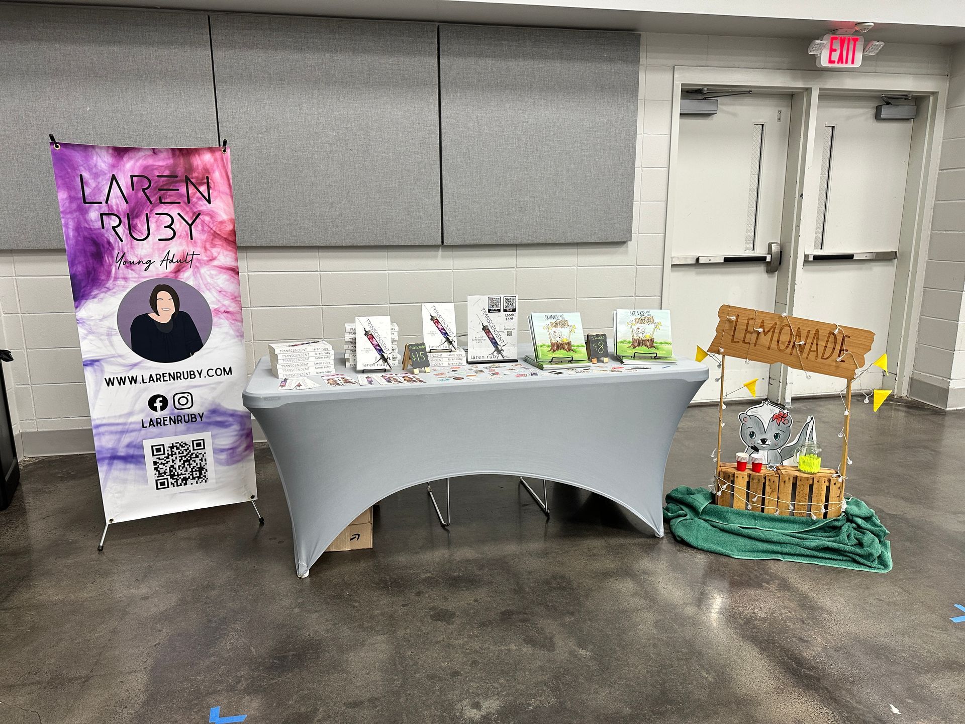 Booth with books and banner, grey table. Sign: 