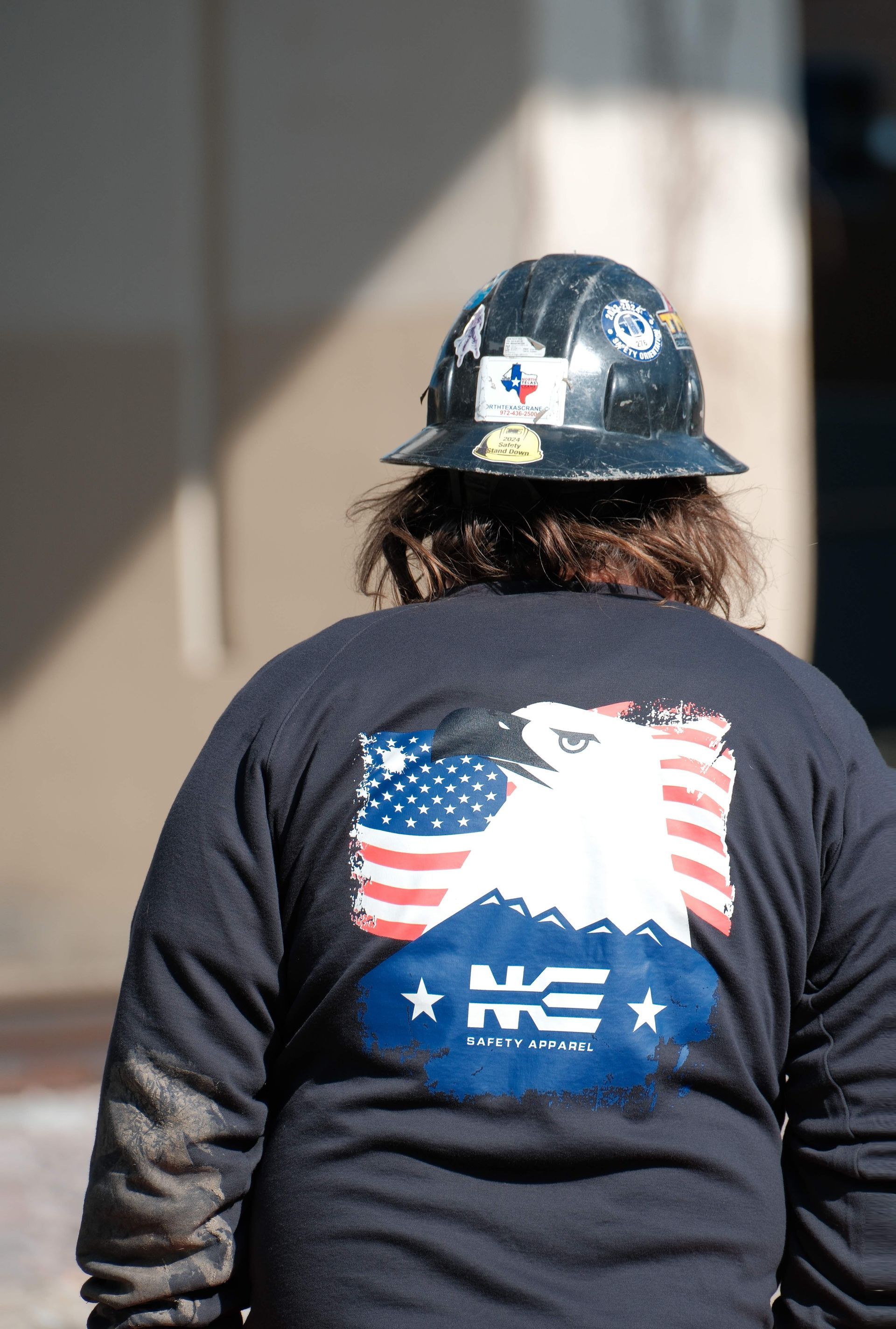 A man wearing a hard hat and a shirt with an american flag on the back