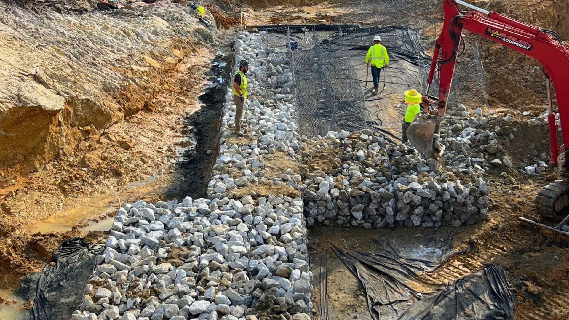a group of construction workers are working on a rock wall .