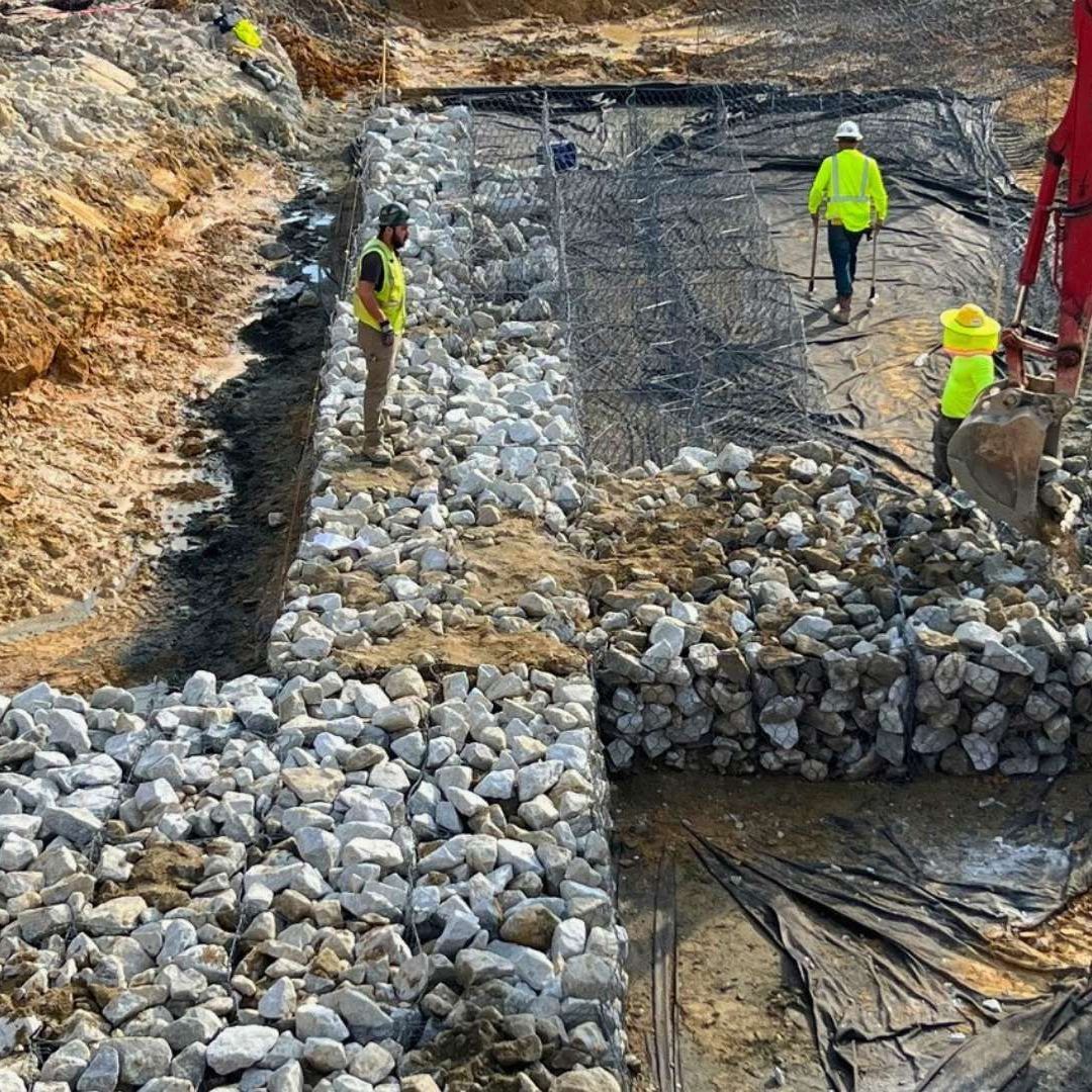 a group of construction workers are working on a rock wall .