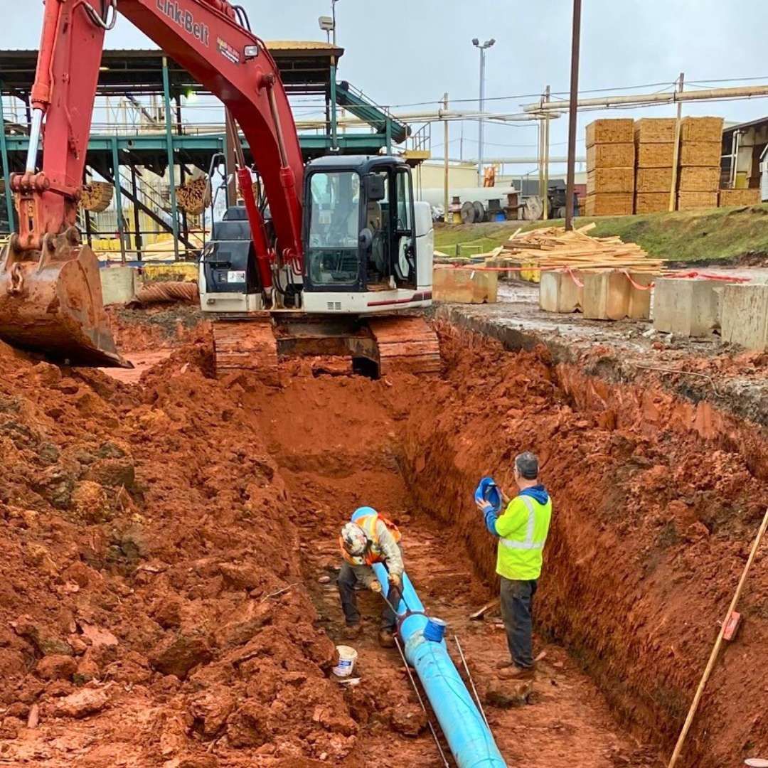 a man is standing in a trench next to a bulldozer .