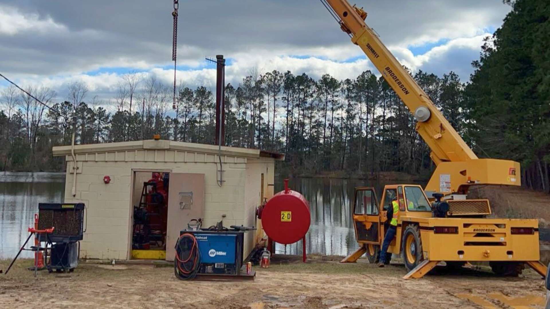 a large yellow crane is lifting a large red tank