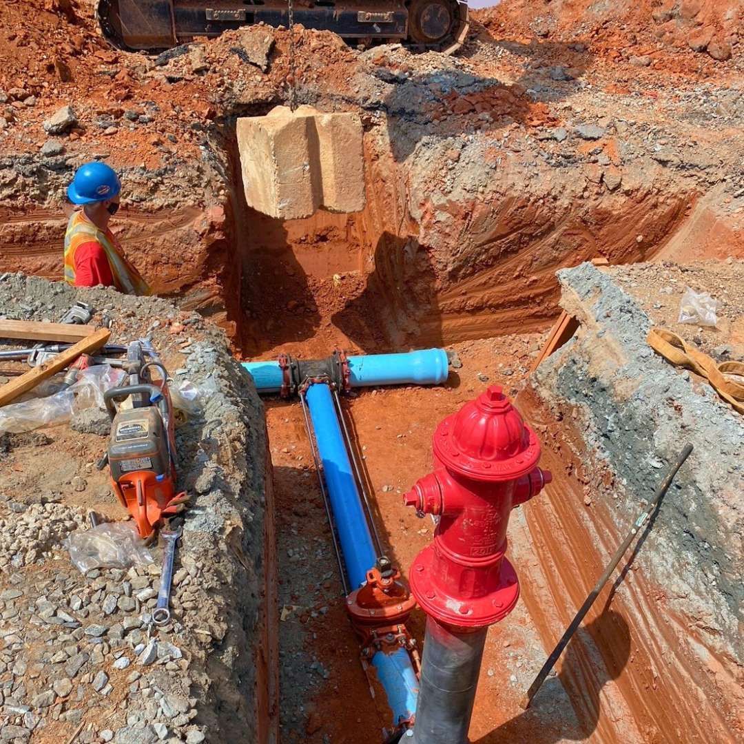 a red fire hydrant is sitting in the dirt next to a blue pipe .