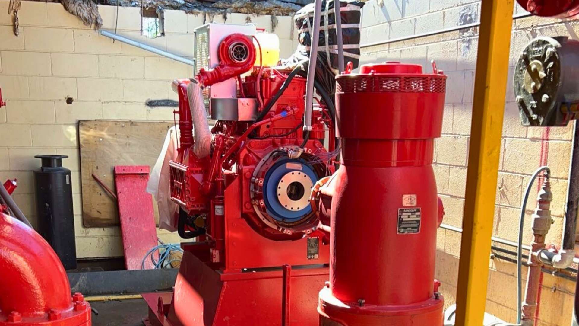 a red engine is sitting in a room next to a yellow pole .