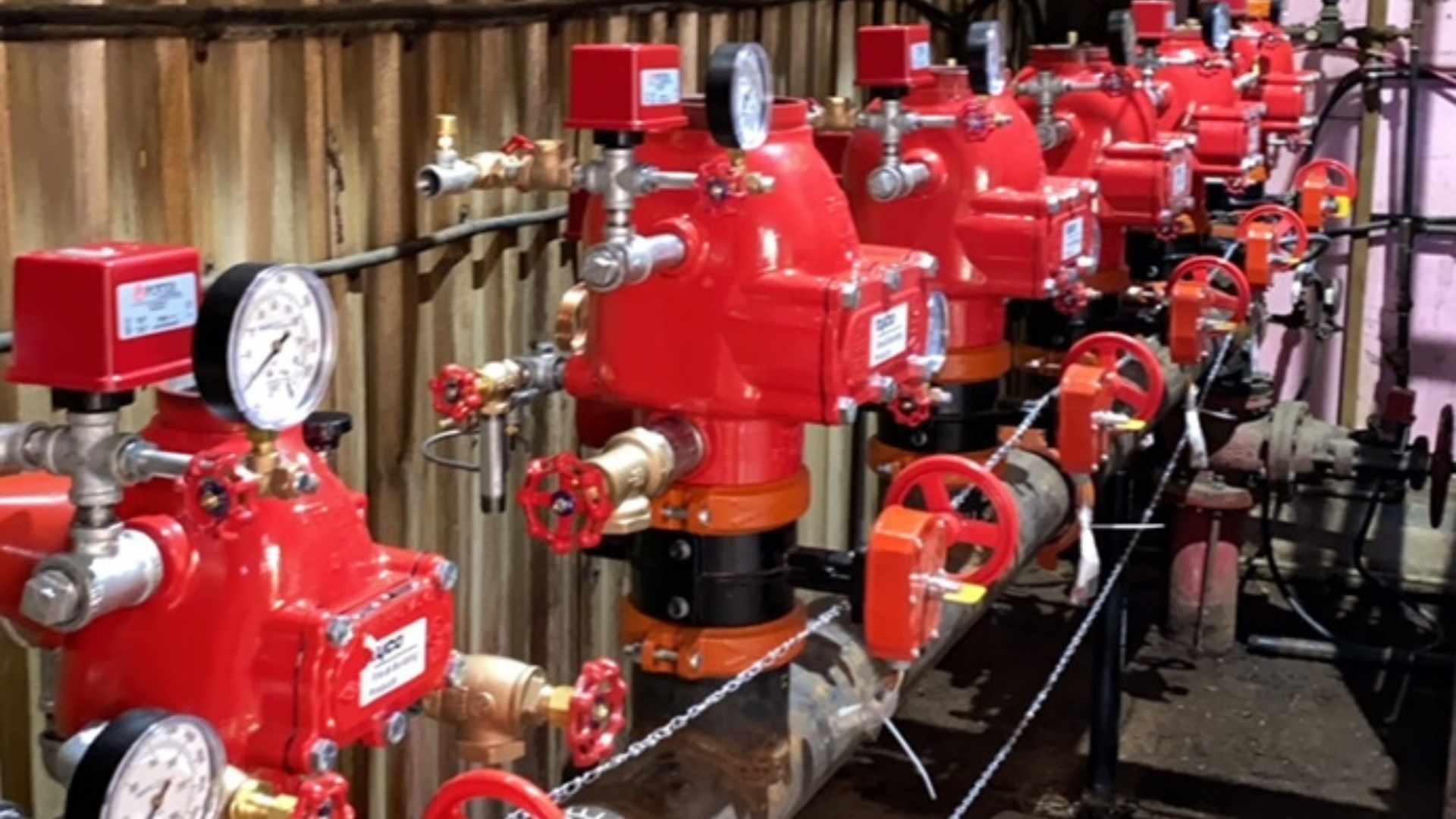 a row of red valves and gauges on a pipe .