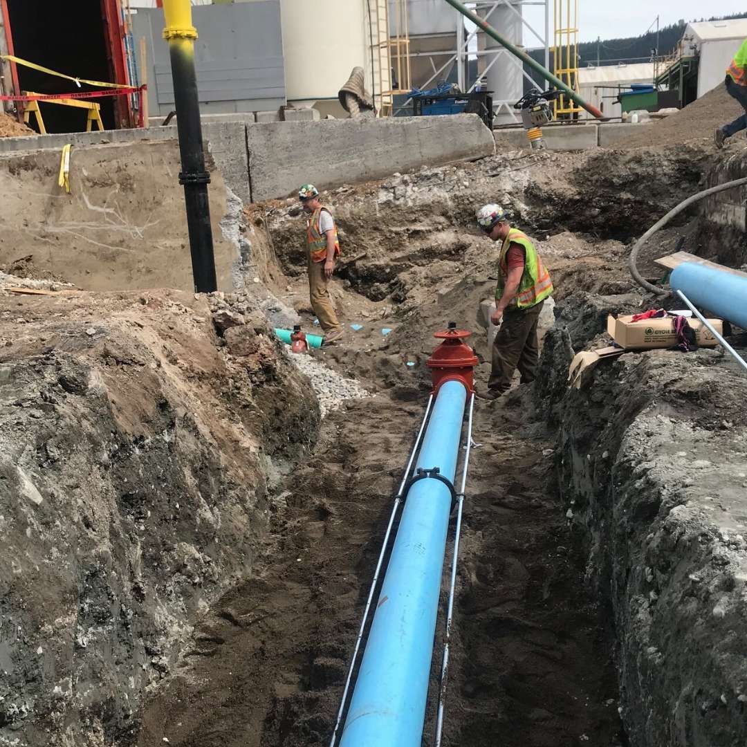 a man is working on a blue pipe in the dirt