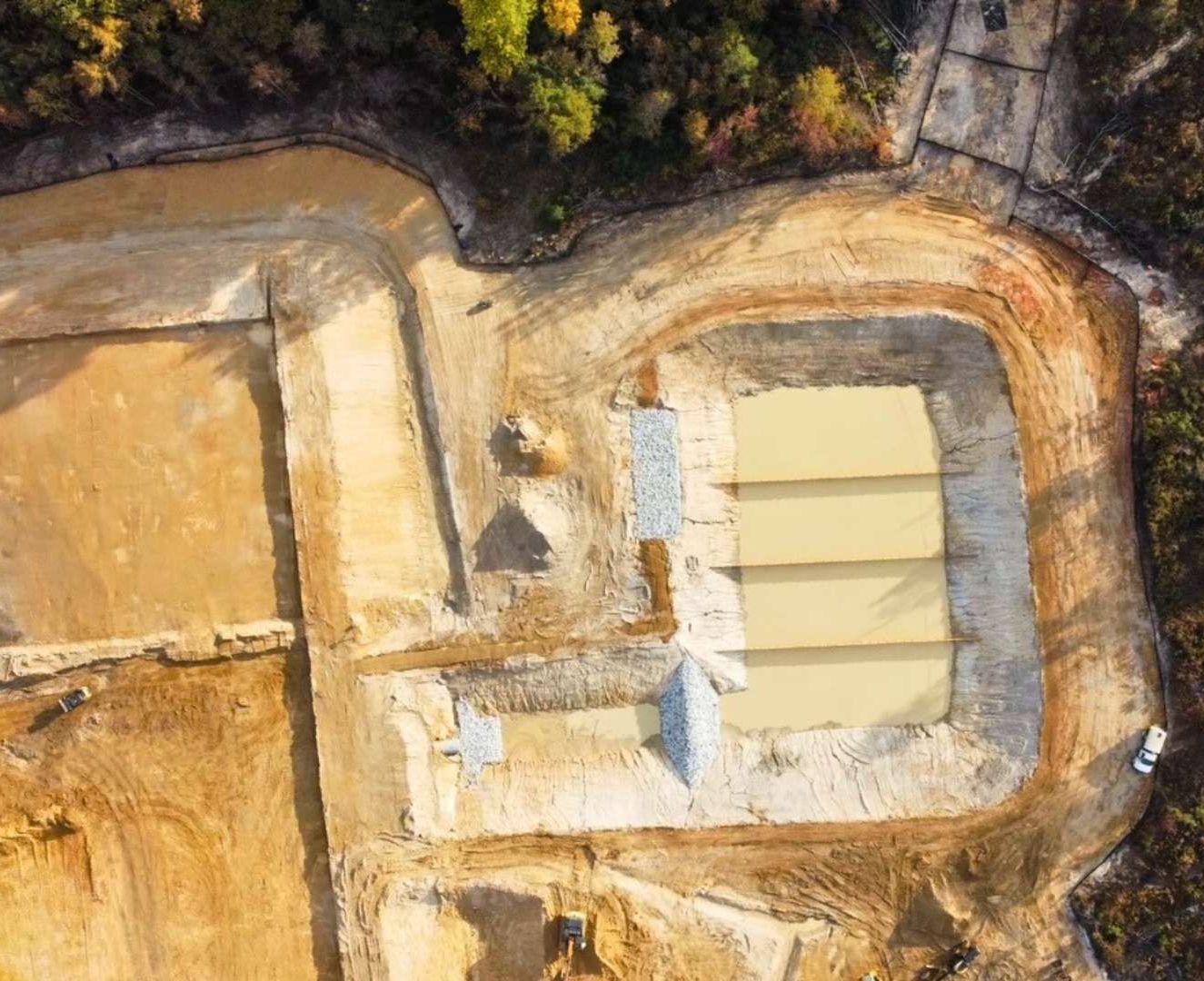 an aerial view of a construction site with a lot of dirt and trees .