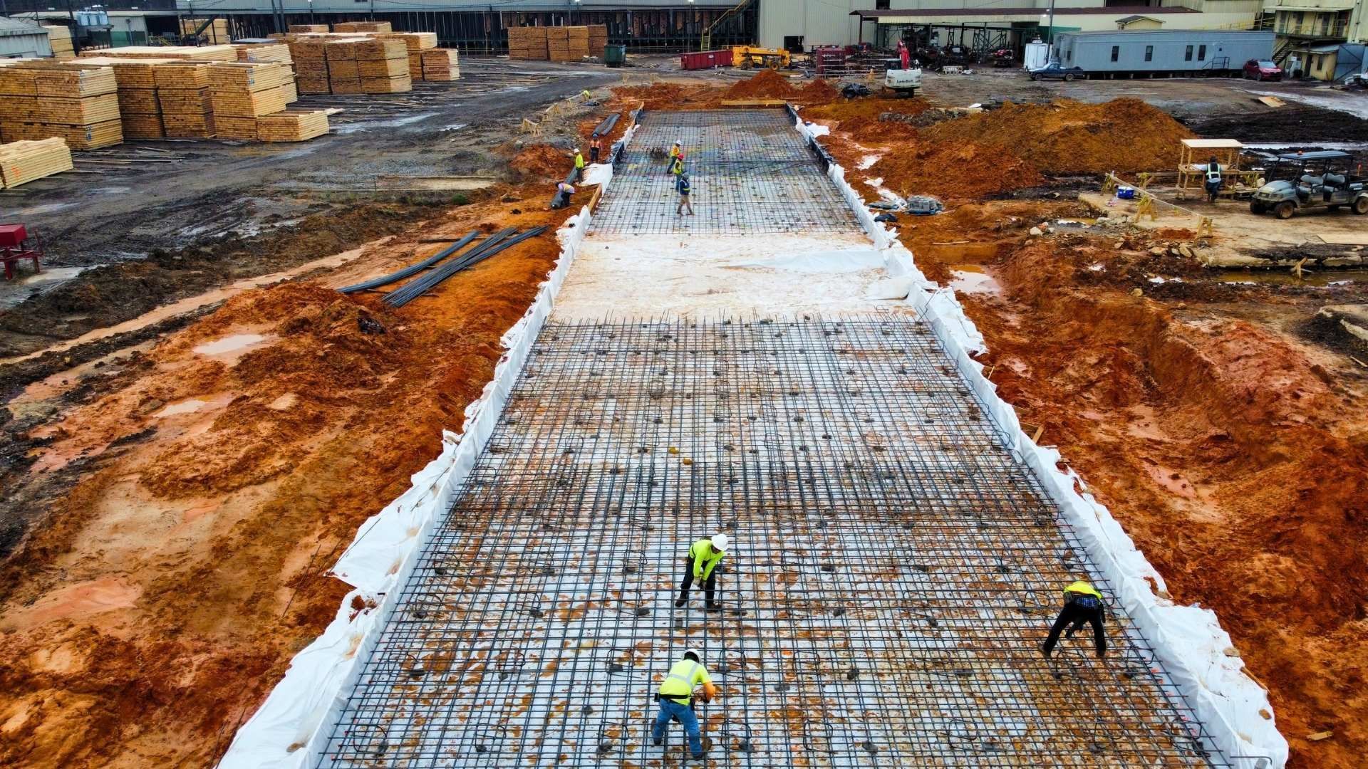 a group of construction workers are working on a large concrete slab .