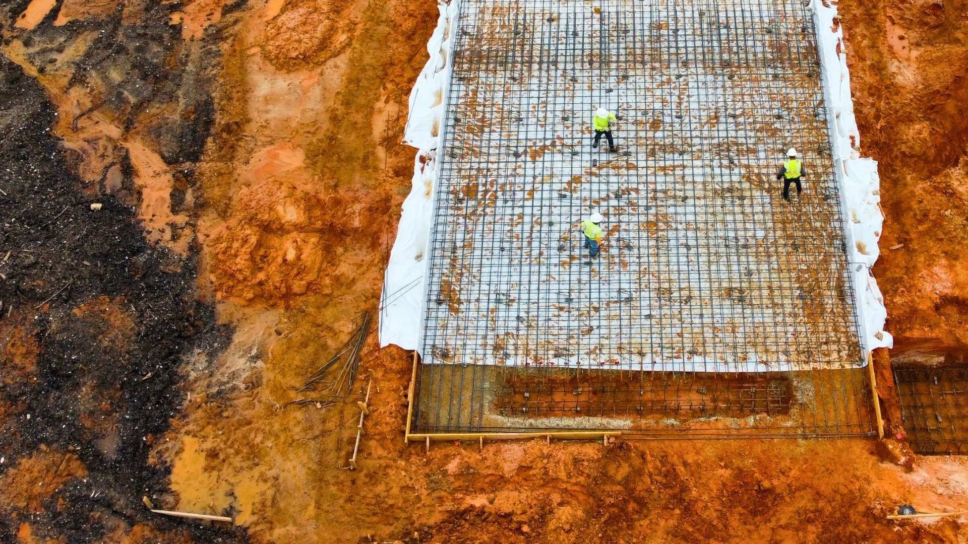 an aerial view of a construction site with workers working on a concrete slab .