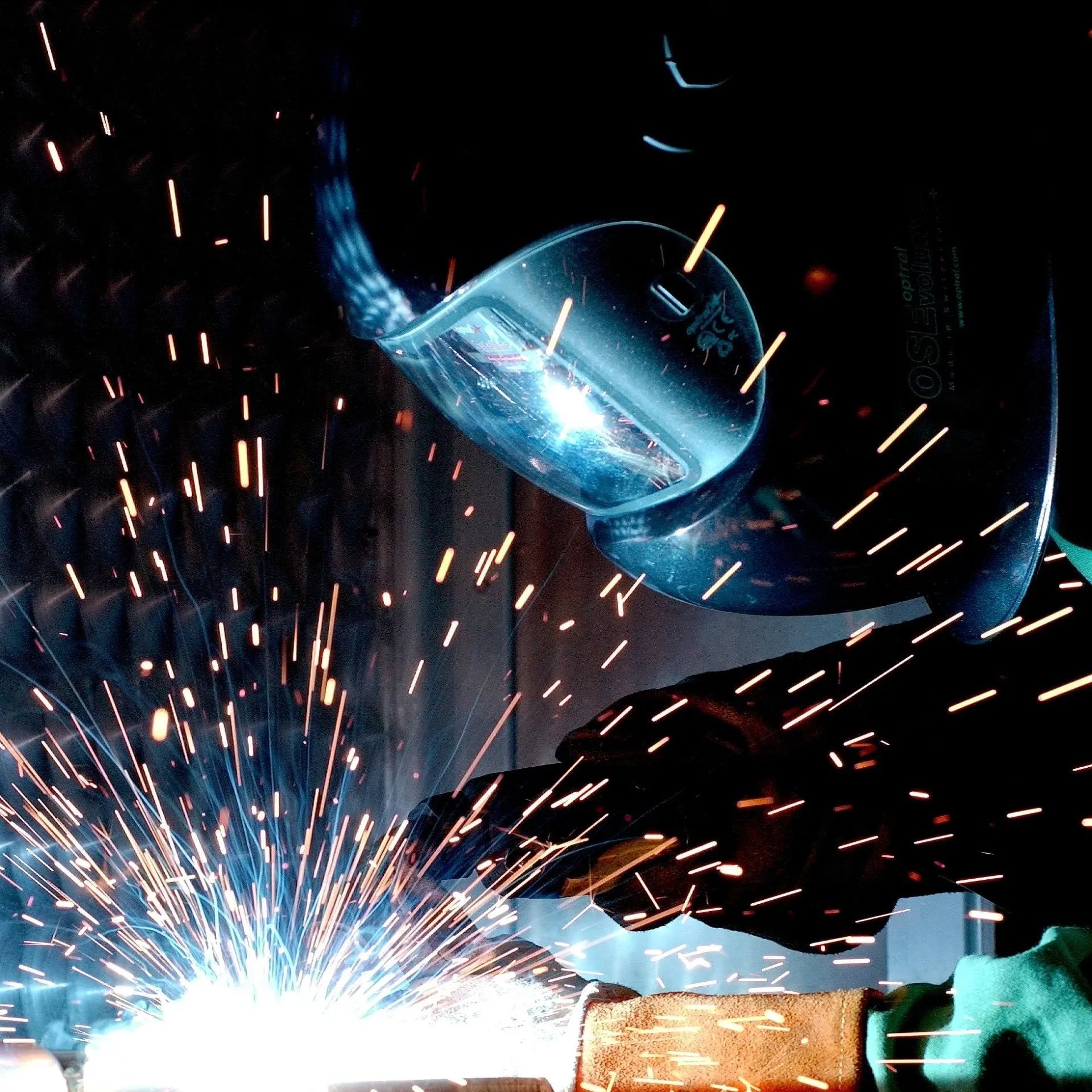 a man wearing a welding helmet is welding a piece of metal