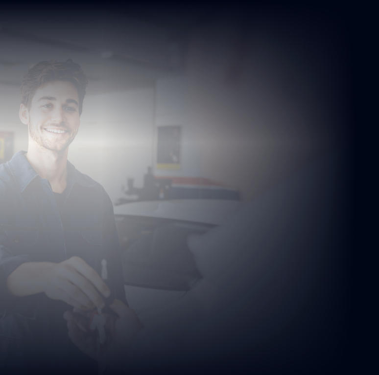 A man is smiling and holding a tablet in a dark room | DAS Auto Werks