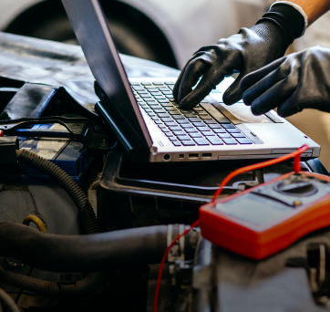 A person wearing gloves is working on a laptop | DAS Auto Werks