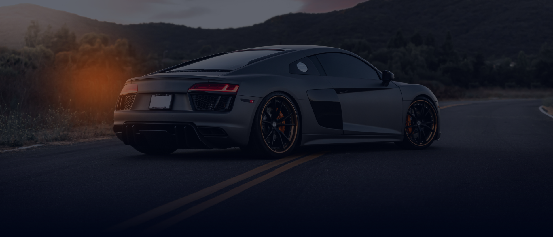 A black sports car is driving down a road at night | DAS Auto Werks